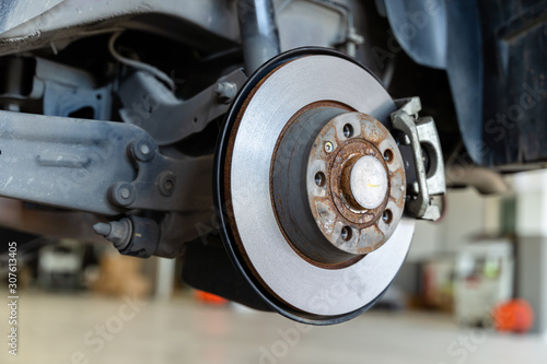 Closeup disc brake of the vehicle damaged , in process of new tire replacement. Car brake repairing in garage © somchairakin