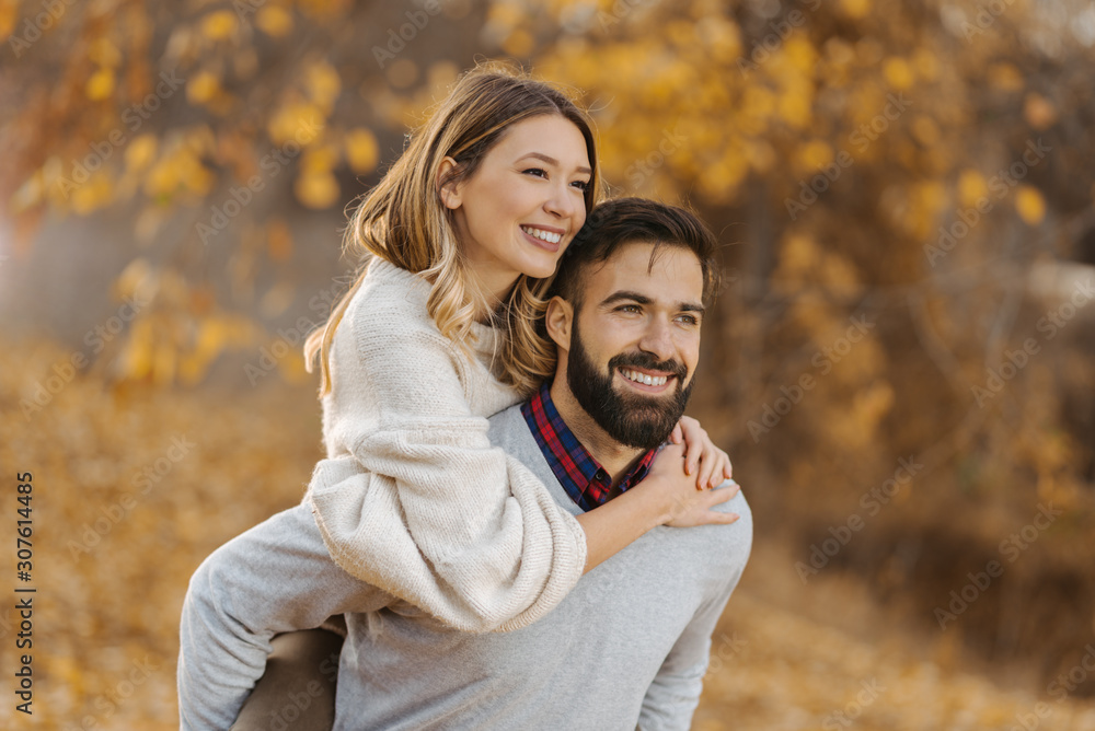 Young cheerful couple having fun while piggybacking in autumn day at the park Young cheerful couple having fun while piggybacking in autumn day at the park