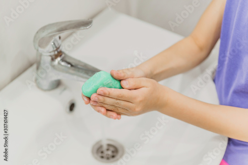 The child washes his hands in the bathroom.  wash hands with soap close-up. concept of hygiene and cleanliness. tap water © Асель Иржанова