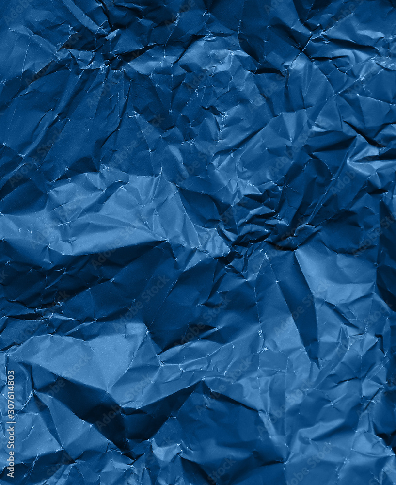 Photo of crumpled paper texture in trendy blue color.