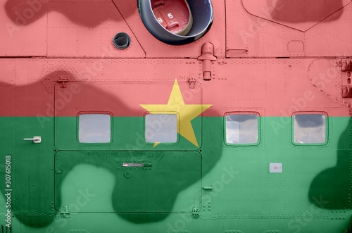 Burkina Faso flag depicted on side part of military armored helicopter closeup. Army forces aircraft conceptual background photo