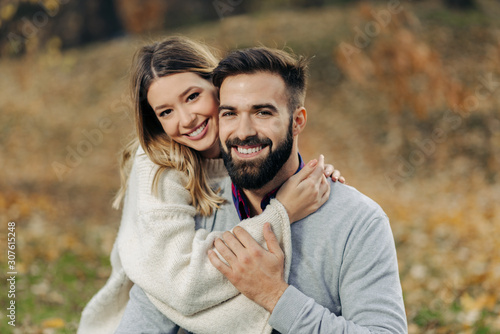 Fotografia Young loving couple enjoying embraced in autumn day and looking at camera