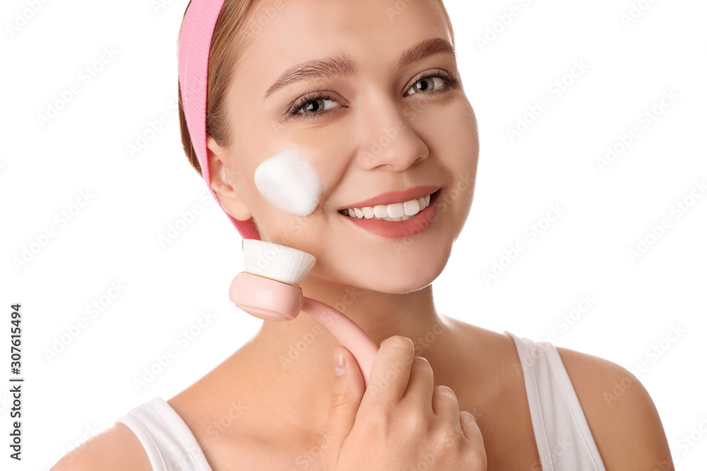 Young woman washing face with brush and cleansing foam on white background. Cosmetic products Young woman washing face with brush and cleansing foam on white background. Cosmetic products
