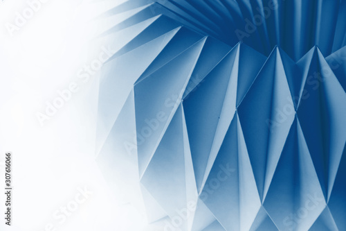 Macro image of white paper folded in geometric shapes, three-dimensional effect, abstract background. Out of focus.