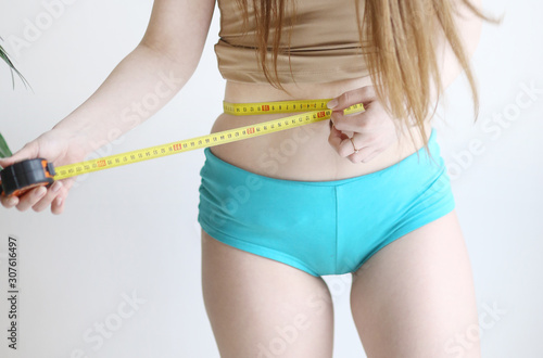 close up photo of model girl measure her waist with measuring tape in blue pants close up photo photo