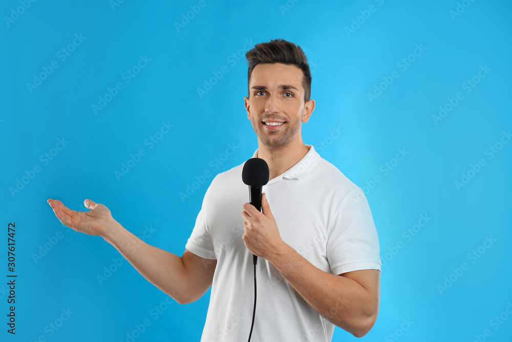 Young male journalist with microphone on blue background Young male journalist with microphone on blue background