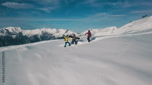 Extreme long shot group of active winter sport people dancing and having fun surrounded by snow. Happy snowboarding and skiing sportsman enjoying and rising hands at ski resort reverse motion