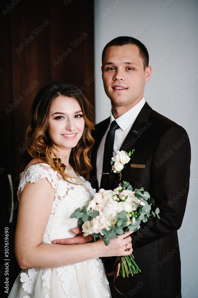 Classic portrait of the bride and groom at home against the background of the room. Happy day young couple. The concept of the holiday and love in the family. Wedding holidays. Classic portrait of the bride and groom at home against the background of the room. Happy day young couple. The concept of the holiday and love in the family. Wedding holidays.