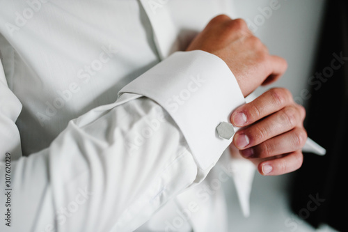 Hand's groom wears a metallic silver cufflinks stud. Wedding morning.