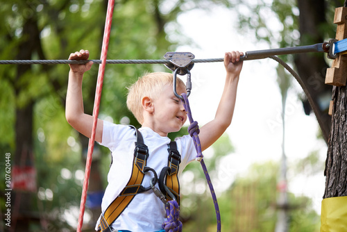 Little boy overcomes the obstacle in the rope park.
