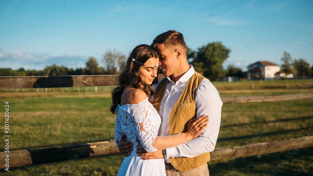 Boho style wedding. Beautiful and stylish couple bride and groom on a nature horse farm. Alone in the field green background. Boho style wedding. Beautiful and stylish couple bride and groom on a nature horse farm. Alone in the field green background.