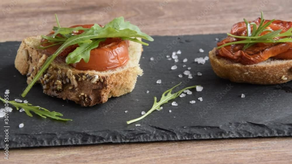 Delicious homemade bruschetta with whole grain bread, grilled tomatoes and fresh arugula. Vegetarian healthy snack, vegan food Delicious homemade bruschetta with whole grain bread, grilled tomatoes and fresh arugula. Vegetarian healthy snack, vegan food
