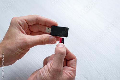 Inserting mini SD memory card in card reader concept. Hand holding memory card and inserts it into the usb reader.