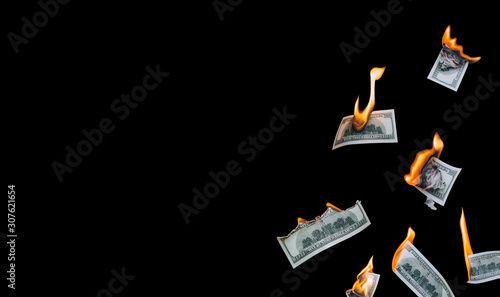 Several 100 dollar bills, falling down, burn on a black background. The concept of bankruptcy, depreciation, devaluation, wastefulness and waste of money. Copy space, isolated.