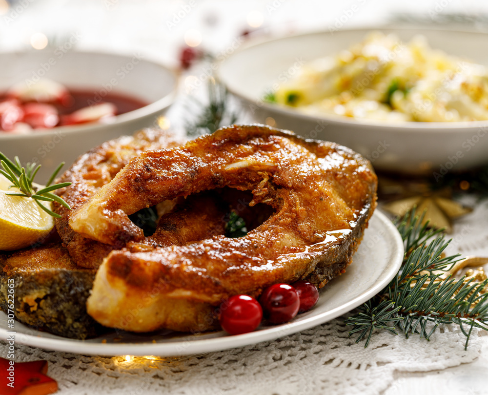 Christmas carp, Fried carp fish slices on a white plate on a holiday table, close up. Traditional christmas eve dish. Polish Christmas Christmas carp, Fried carp fish slices on a white plate on a holiday table, close up. Traditional christmas eve dish. Polish Christmas