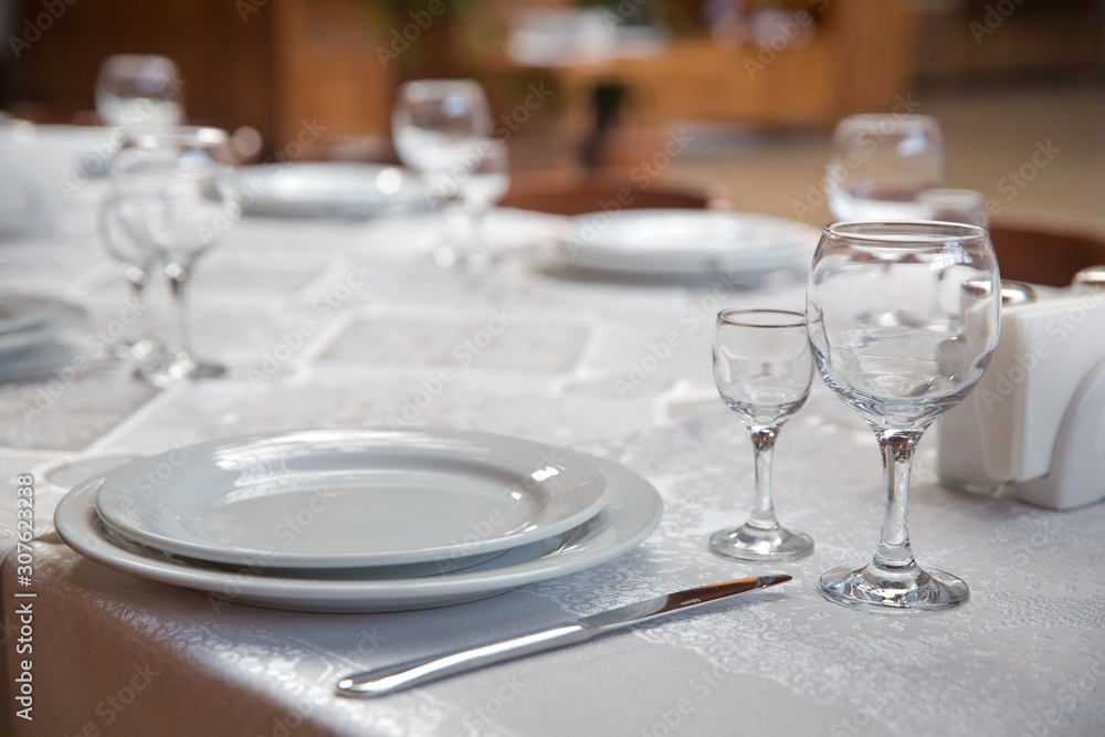 Tables set for meal . fork, knife . empty glasses and plates on the table in the restaurant . Tables set for meal . fork, knife . empty glasses and plates on the table in the restaurant .