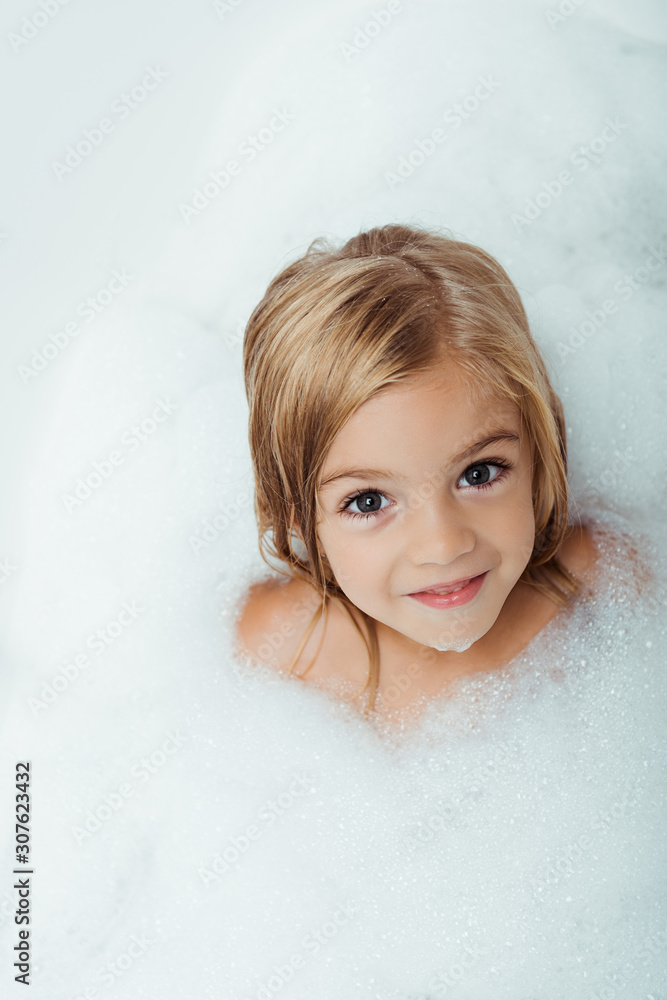 overhead view of cute kid taking bath and looking at camera at home overhead view of cute kid taking bath and looking at camera at home