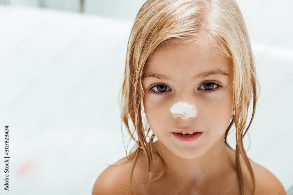 cute naked with bath foam on nose kid taking bath at home foto de Stock