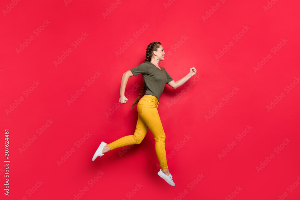 Full size profile photo of millennial lady jumping high sports competition marathon participant running speed wear casual yellow pants green t-shirt isolated red color background