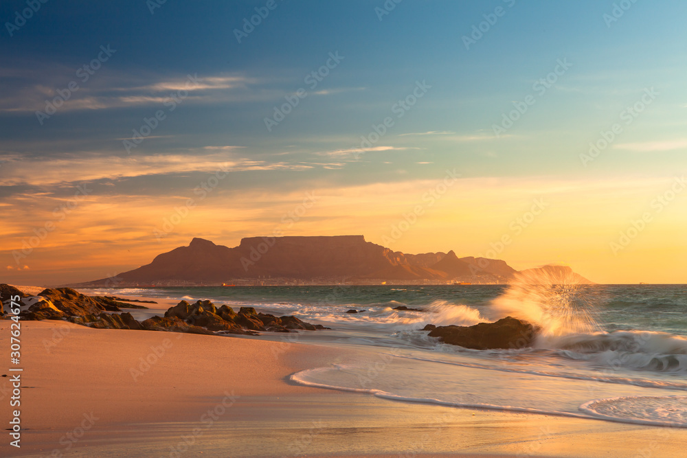 Obraz premium malowniczy widok na góry stołowe kapsztad w południowej afryki z blouberg na złoty zachód słońca z rozpryskiwaniem fal