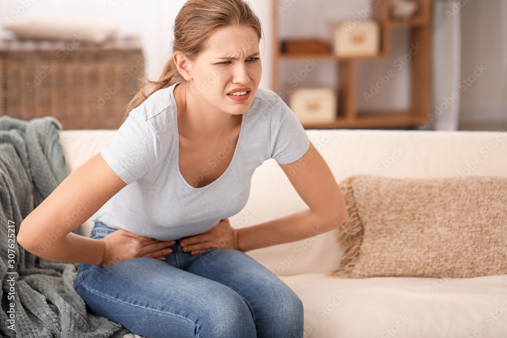 Young woman suffering from abdominal pain at home Young woman suffering from abdominal pain at home