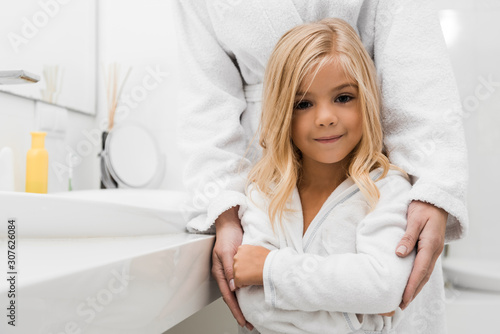 cute daughter standing with mother in bathroom