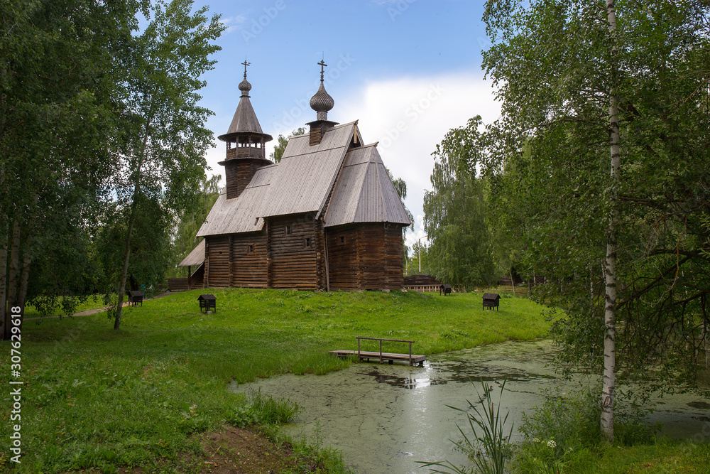 The old wooden Church is surrounded by birches on the shore of the pond. Kostroma, Russia.