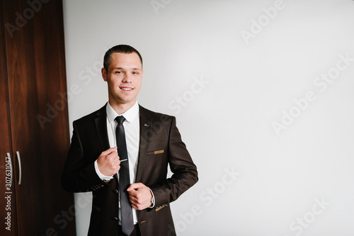 Portrait of a young attractive handsome businessman stylish smiling man in a suit standing against background room.