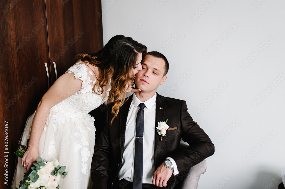 Beautiful bride with a bouquet of wedding flowers and the groom with a boutonniere on a suit. Wedding ceremony. Woman kiss a man. Beautiful bride with a bouquet of wedding flowers and the groom with a boutonniere on a suit. Wedding ceremony. Woman kiss a man.