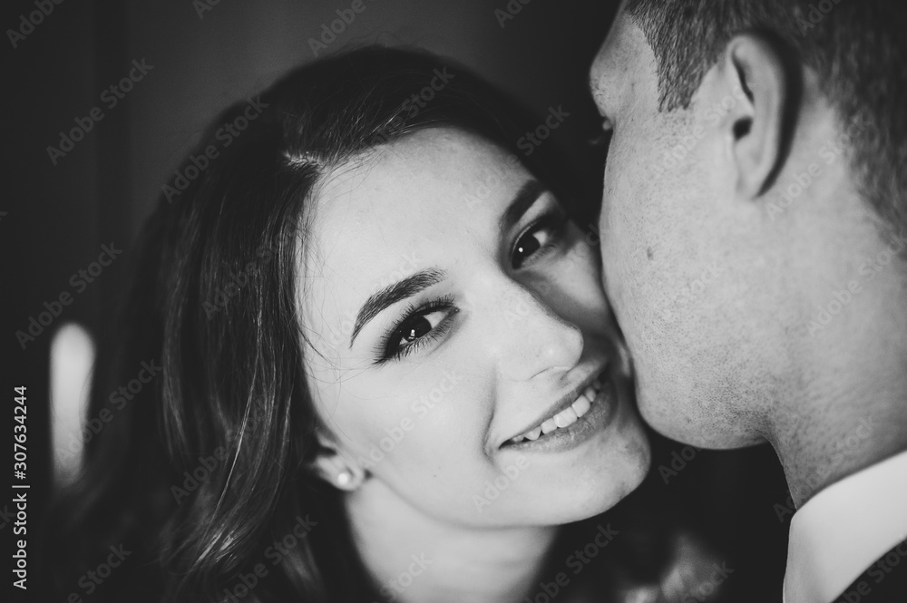 Fototapeta premium Romantic black and white photo. Man hugs a happy woman. Young couple in love on Valentine's day. International Women's Day. Close up.
