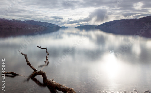 Fototapeta Naklejka Na Ścianę i Meble -  A view across Loch Ness looking down the length of the lake with rocks inn the foreground and dark clouds above, in Scotland, UK
