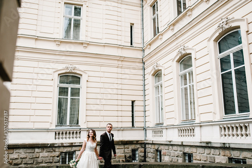 Newlyweds are walking near ancient restored architecture, old building, old house outside, vintage palace outdoor.