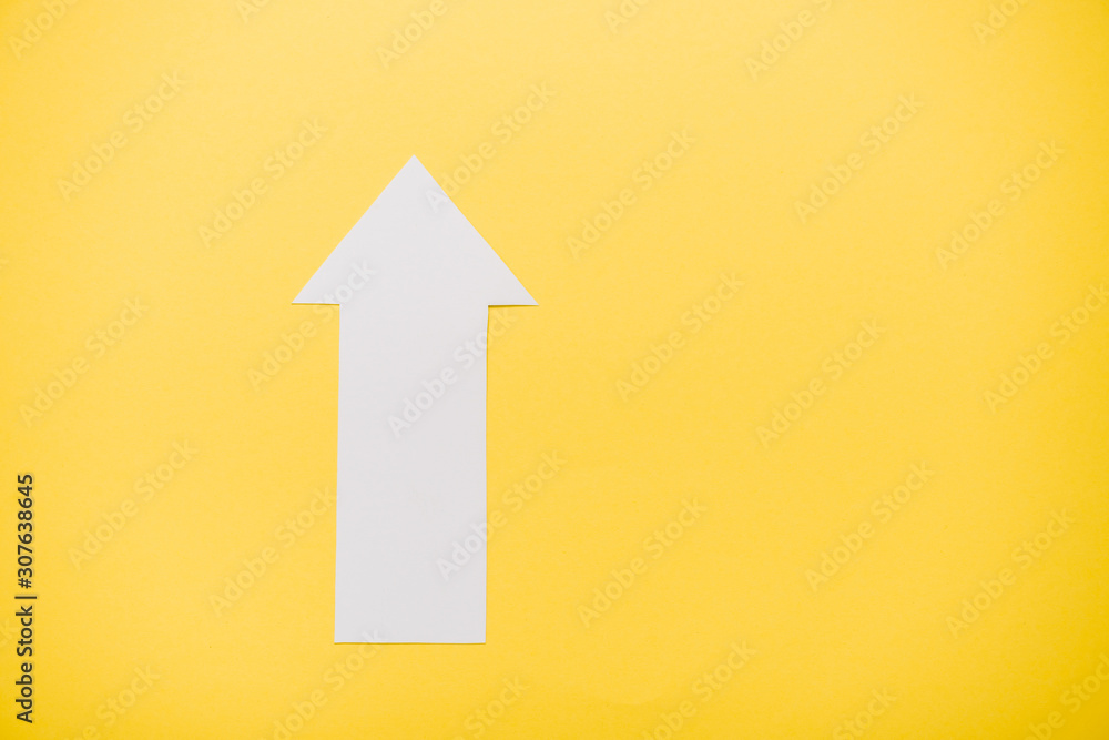 top view of white arrow isolated on yellow with copy space top view of white arrow isolated on yellow with copy space