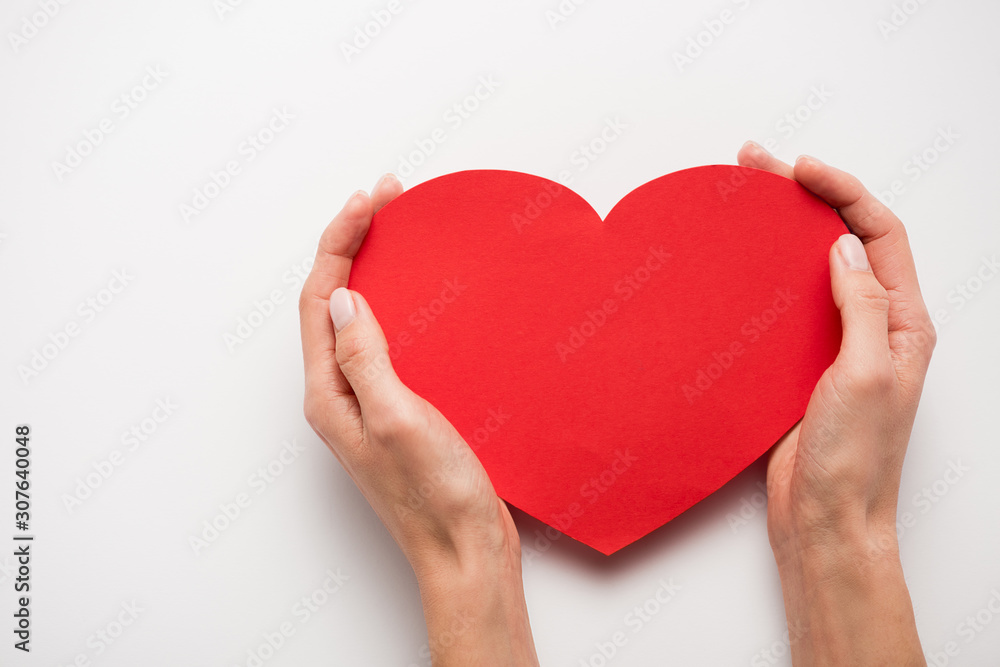 cropped view of woman holding red heart shape paper cut on white