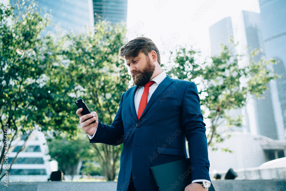 Man in suit checking phone near business center Man in suit checking phone near business center