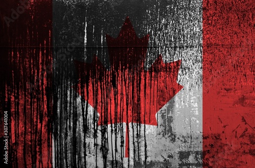 Canada flag depicted in paint colors on old and dirty oil barrel wall closeup. Textured banner on rough background