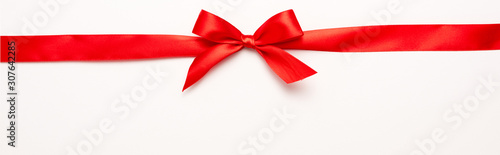 Obraz na plátně Panoramic shot of red ribbon with bow on white