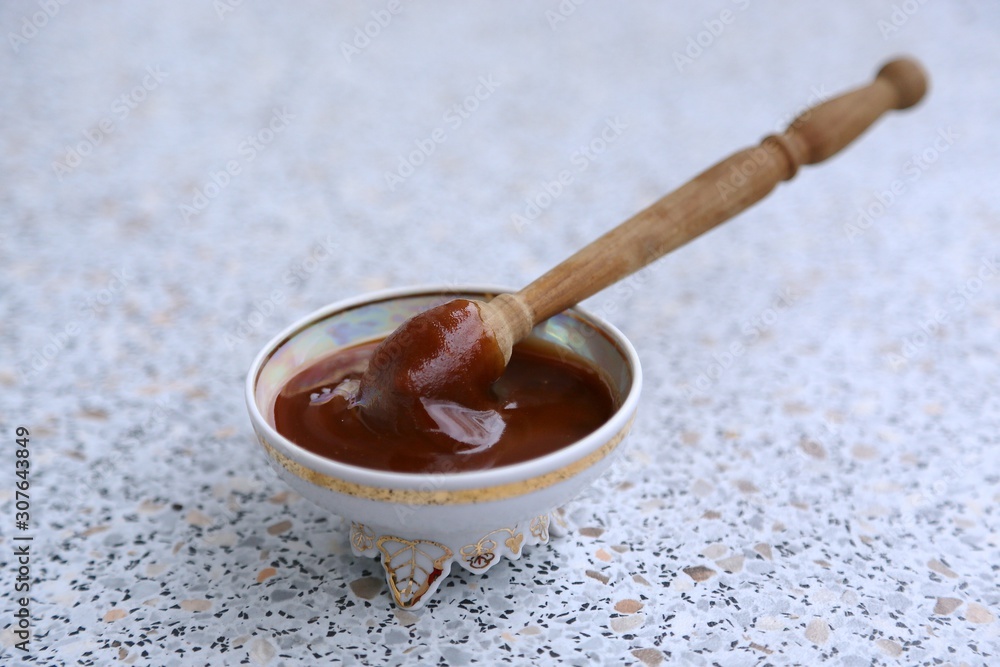 Thick honey and a spoon of wood in a glass plate Thick honey and a spoon of wood in a glass plate