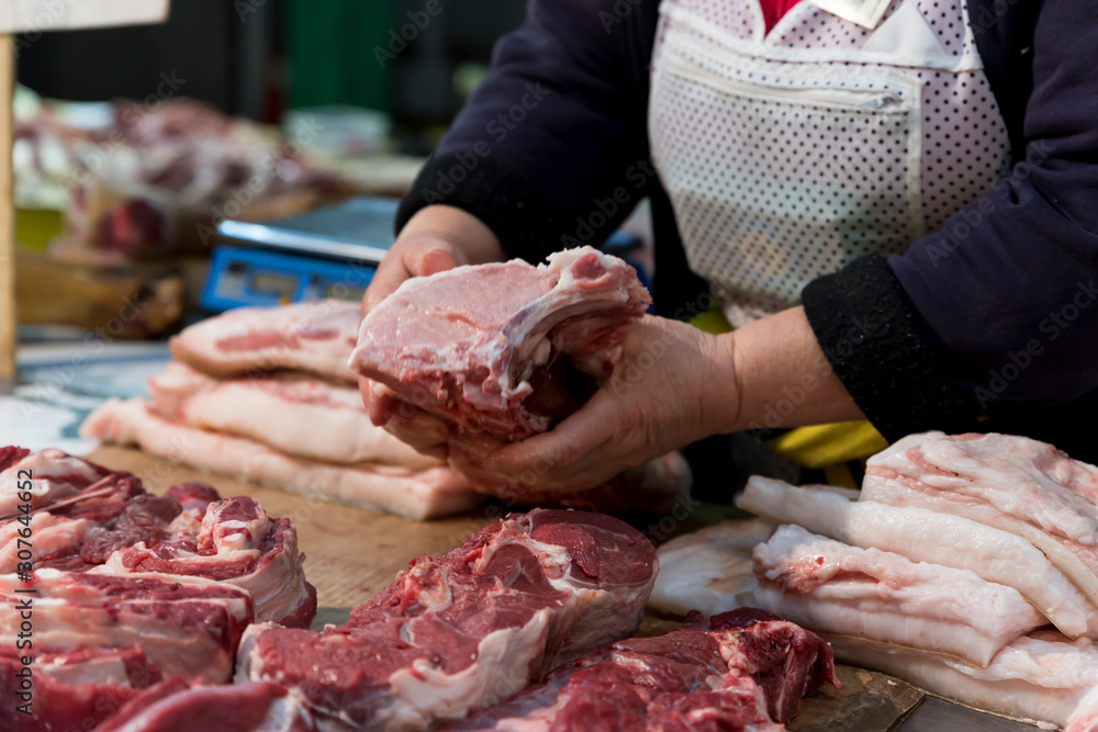 Piece of raw meat in the hands of the seller at the grocery market.