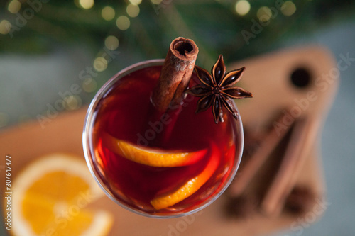 Mulled wine with spices and a Christmas tree on a green background.