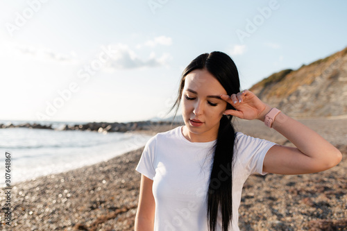 The concept of sport. Young brunette woman tired after workout. In the background mountains  sea and wild beach