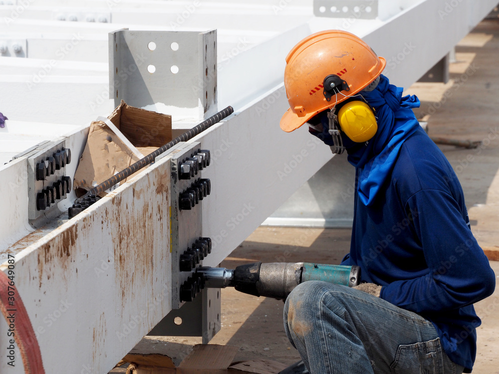 Worker using a drill in a construction site Worker using a drill in a construction site