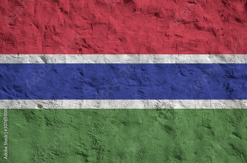 Gambia flag depicted in bright paint colors on old relief plastering wall. Textured banner on rough background photo