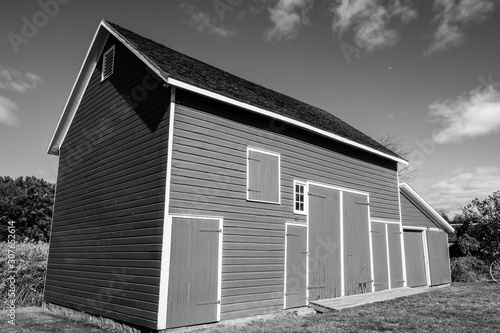 Fototapeta Naklejka Na Ścianę i Meble -  Isolated red barn in wooded area. Red farm barn building exterior. 