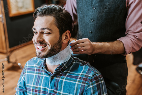 barber fixing collar around neck of happy man