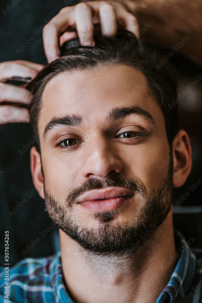 Fototapeta premium barber with black hair pomade on hands styling hair of bearded man