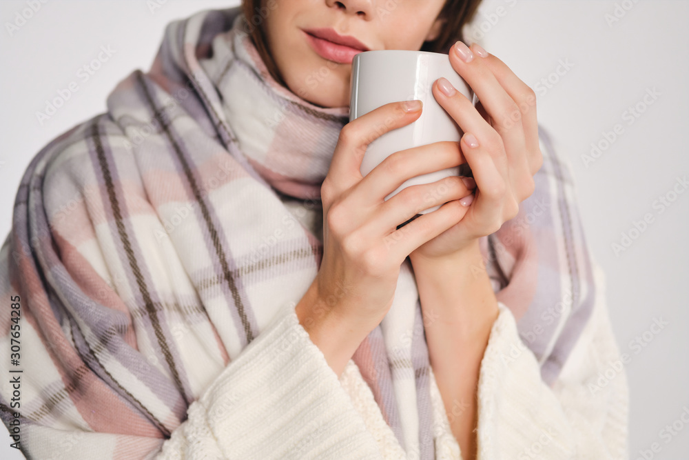 Close up attractive girl with scarf holding cup with warm drink near face over white background Close up attractive girl with scarf holding cup with warm drink near face over white background