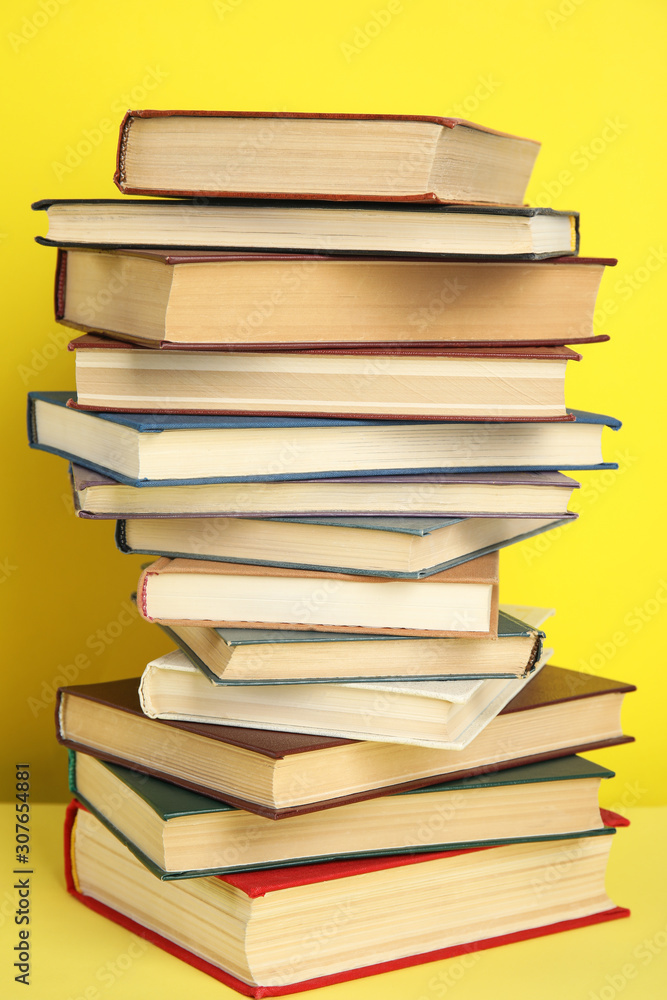 Stack of different hardcover books on yellow background Stack of different hardcover books on yellow background