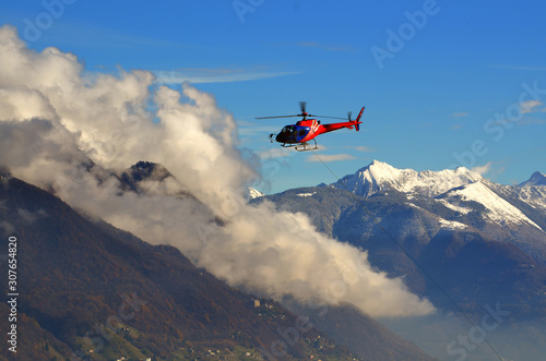 Flying Helicopter with Clouds and Snow-capped Mountain in Switzerland.