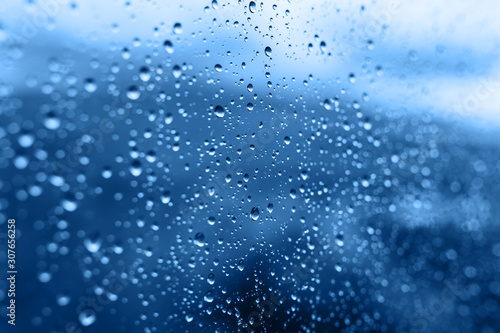 Blurred raindrops on the glass background Classic blue color 